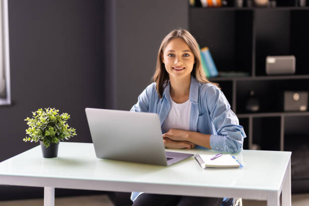 istock Beautiful business woman sit indoors in office using laptop computer. 1438753487