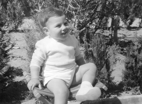Black and white Image from the fifties, smiling little boy sitting outdoors portrait