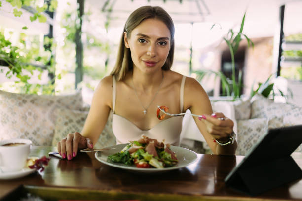 istock Beautiful woman using digital tablet with salad at cafe 1438755636