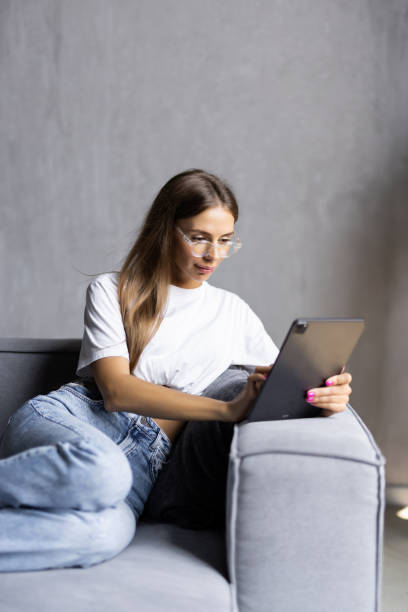 istock Smiling young woman use tablet on the sofa 1438755734