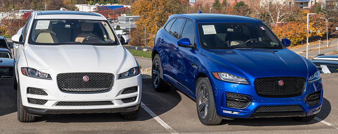 Monroeville, Pennsylvania, USA October 30, 2022 Two different Jaguar SUVs, one blue and the other white for sale at a dealership on a sunny fall day