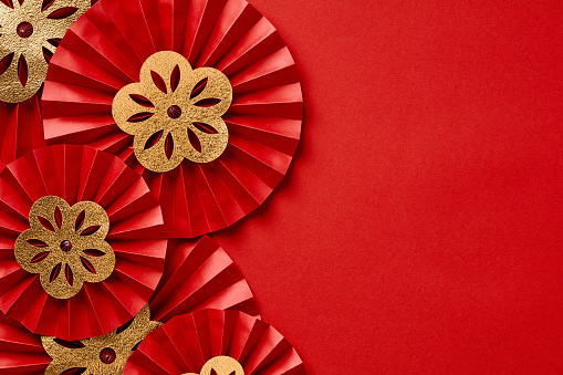 Chinese New Year festival or wedding decorations on red background. Red paper fans with gold decorations top view. Lunar New Year celebration concept. Flat lay, top view.