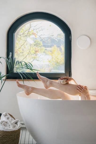 istock Female raised feet up, washing her legs with sponge 1438756893
