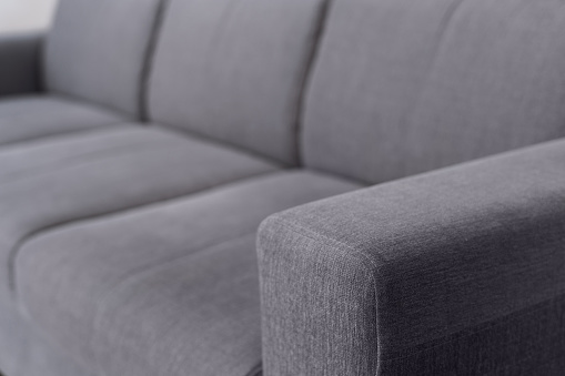 closeup of grey textile on comfortable couch in living room at modern apartment, repair and restoration furniture concept
