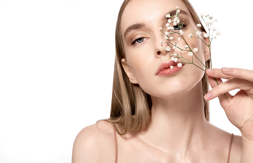 Close-up of a young woman with perfect clean soft skin. A conceptual portrait of a girl with a flower, a symbol of ecological and natural cosmetics.