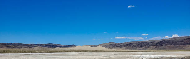 istock Sand dunes in a remote Nevada valley. Wide panoramic view under bright blue sky. 1438761972