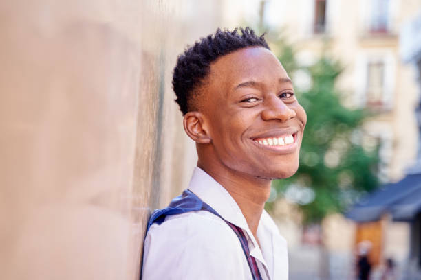 istock handsome african-american man showing white teeth leaning against the wall 1438762438