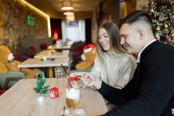 istock Young couple enjoying hot chocolate and using digital tablet in restaurant during Christmas holidays 1438769053
