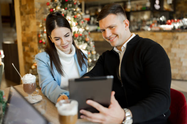 istock Young couple enjoying hot chocolate and using digital tablet in restaurant during Christmas holidays 1438769328