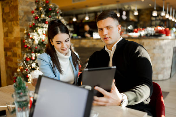 istock Young couple enjoying hot chocolate and using digital tablet in restaurant during Christmas holidays 1438769332