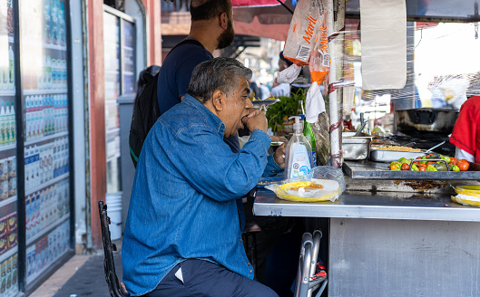 Mexico City Mexico - February 15 2022: A man sitting down eating at a food cart in Mexico City