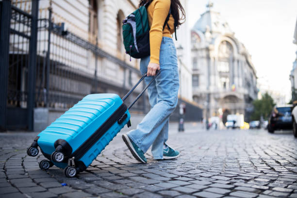 istock Unrecognizable tourist walking on street with suitcase. 1438774324