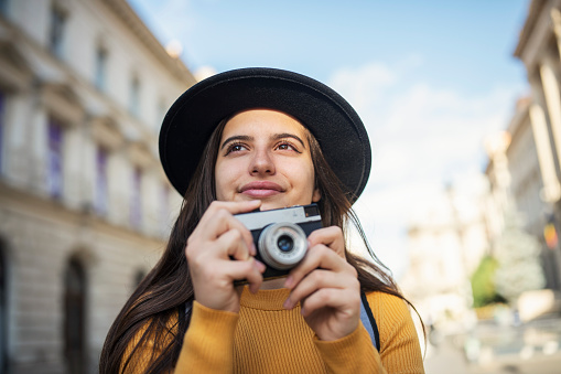 Portrait of a female tourist taking photos with a retro camera.
