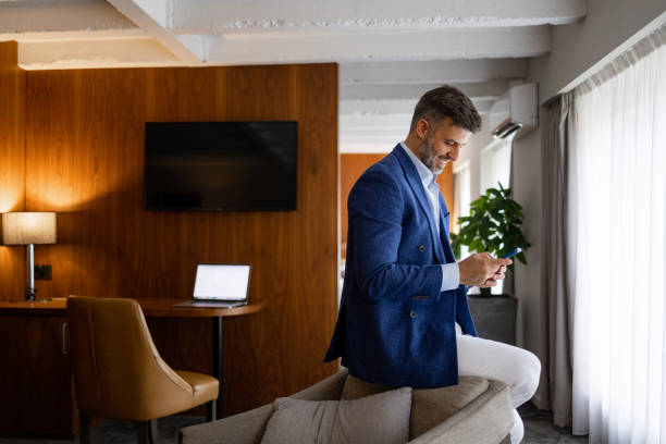 istock Happy middle-aged men sitting on armchair and using mobile phone 1438774446