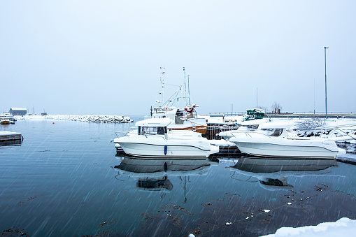 Fishing boats are moored at Hansnes pier during heavy snow. Hansnes is a village located along the Langsundet strait, about 58 kilometers northeast of the city of Tromsø.