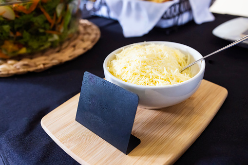 A piece of aged Parmesan cheese with fresh basil leaves on a white background with copy space