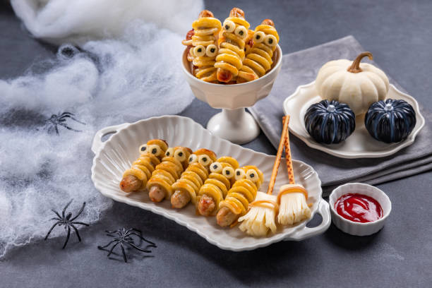 Spooky sausage mummies on black background, Halloween treat