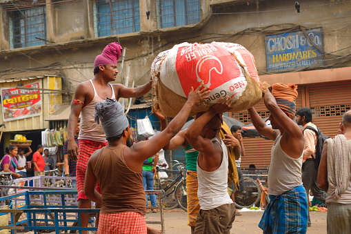 Kolkata, India - March 26, 2017: A group of labourers lifting a heavy baggage.