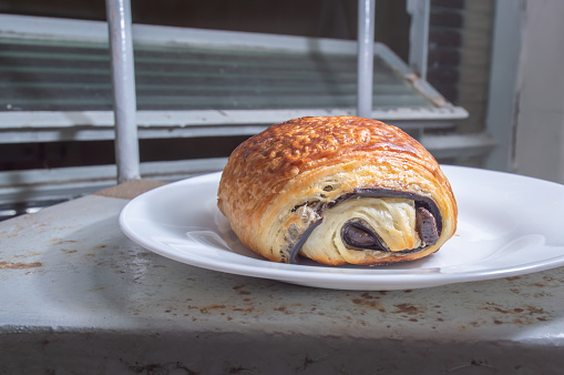 Pain au Chocolat on a white dish with natural light chocolate bread with foled dough.