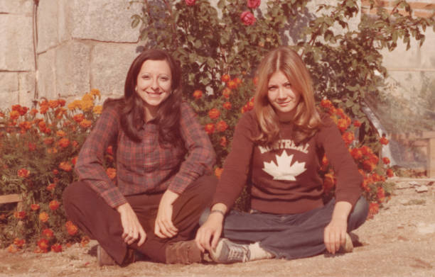 Imagem tirada nos anos 70: Jovens mulheres lésbicas sorridentes posando sentadas no chão - foto de acervo