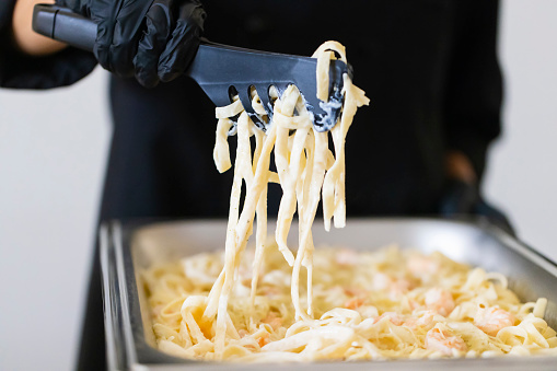 Cook serving pasta with tongs