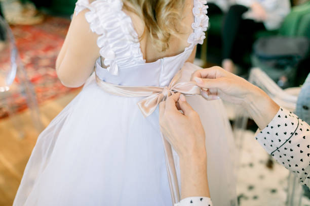 Woman tying the back of a flower girl's dress Woman tying the back of a flower girl's dress flower girl stock pictures, royalty-free photos & images