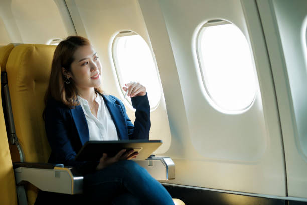 istock Business woman working on tablet while sitting in airplane. 1438829092