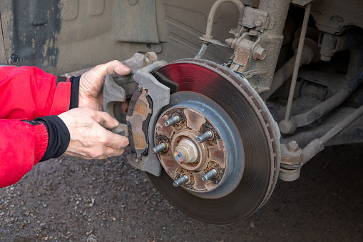 A man replaces the brake pads on a car. Security, service.