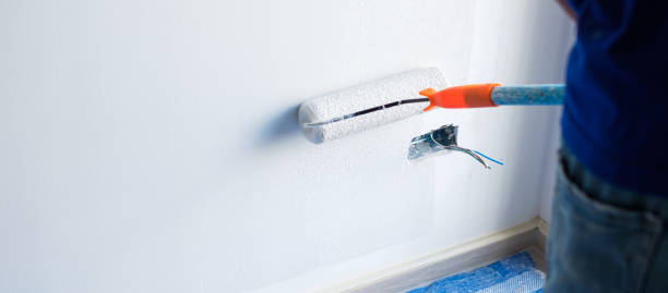 istock painter man with paint roller brush painting the wall. Renovation, maintenance and development of home or apartment 1438834429