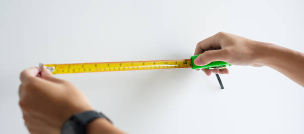 istock Man hand using tape measure for measuring with wall backgrounds at home. DIY, Interior design, repairing and improvement home or apartment concepts 1438834494
