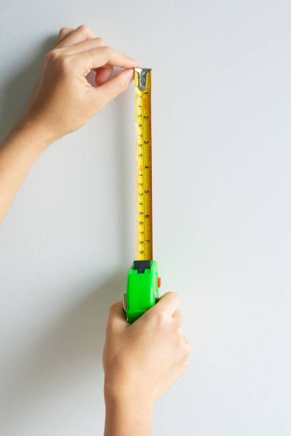 istock Man hand using tape measure for measuring with wall backgrounds at home. DIY, Interior design, repairing and improvement home or apartment concepts 1438834517