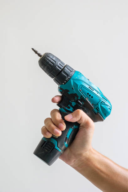 man hand holding cordless screwdriver with wall background, Carpenter working with electric screwdriver on the work