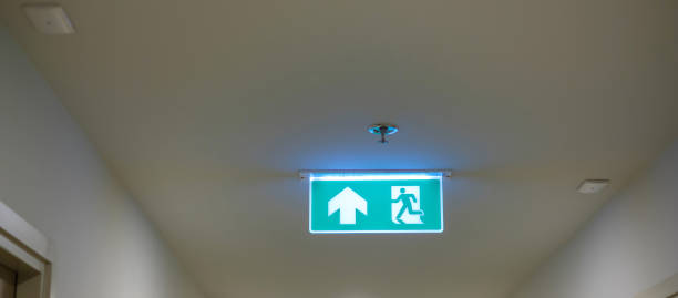istock Fire Emergency exit sign on the wall background inside building. Safety concept 1438835976