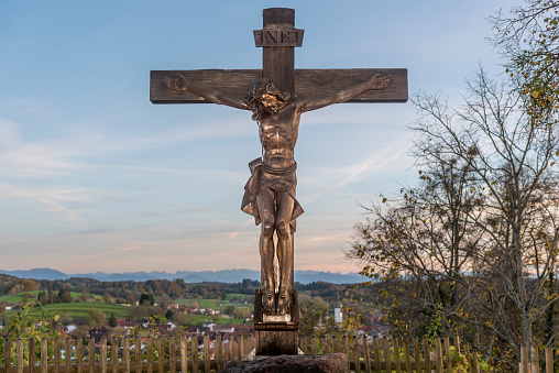 Jesus crucified on wooden cross at Andechs monastery with sky, horizon and Bavarian alpine foothills