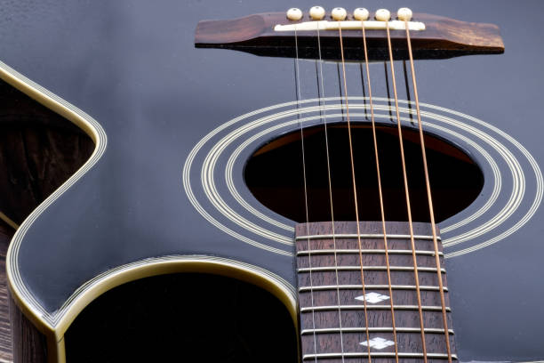 istock Acoustic black guitar on wooden table and white background. 1438841584