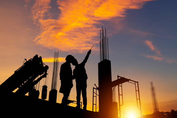 istock Silhouette of Engineer and worker checking project at building site background, construction site at sunset in evening time 1438841664