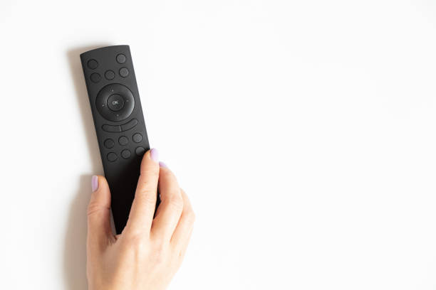 istock Remote control in a female hand on a white background close-up, TV 1438844043