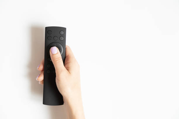 Remote control in a female hand on a white background close-up, TV stock photo