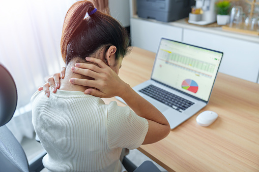 Woman having Neck and Shoulder pain during work long time on workplace. due to fibromyalgia, rheumatism, Scapular pain, office syndrome and ergonomic concept