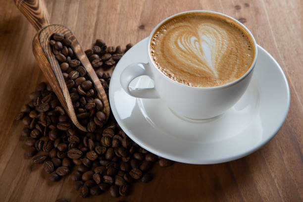istock Roasted coffee beans with cappuccino with heartbeat foam pattern 1438853210