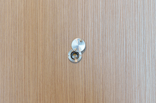 Lens peephole on wood door in apartment room. Security concept