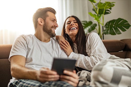 Couple using a tablet in their living room,enjoying together. Online concept.