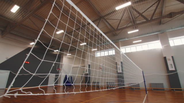 Volleyball net above empty field in sports school gym