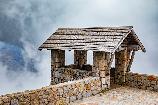 Old heritage stone building in the mountains with dark stormy clouds.