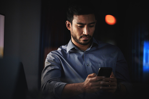 Business man, phone and dark room of a employee working on a job text and social media app scroll. Mobile internet, web and technology of a corporate businessman worker online busy with an email