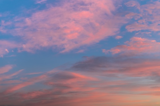 A beautiful shot of pink clouds in a clear blue sky with a scenery of sunrise