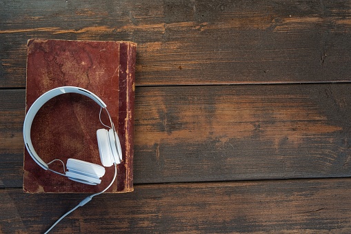 A white headphones on old book against rural wooden background
