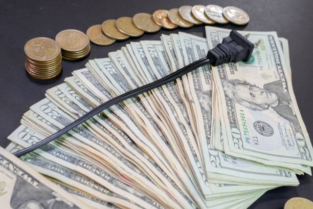 istock dollar bills and coins with an electric plug. 1438865005