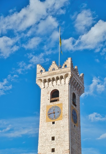 A vertical shot of the tower in Piazza Duomo, Trento with a blue cloudy sky in the background, Italy
