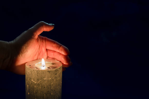 istock one burning candle with hand protecting the flame copy space 1438865470